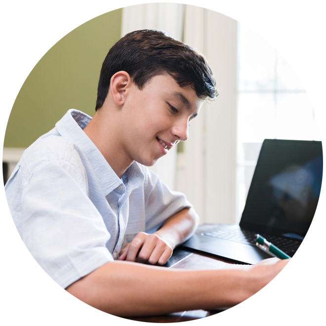 young man writing next to laptop